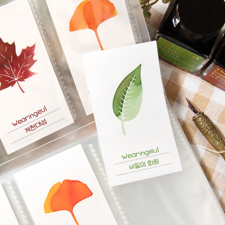 Wearingeul Ash Leaf Ink Swatch Cards, featuring watercolor leaf illustrations, paired with The Secret Garden fountain pen ink bottles and a calligraphy nib on cloth.