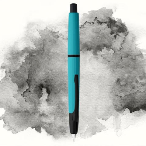 Moonman/Majohn A2 fountain pen in Peacock Blue with matte black clip and extra fine nib, set against a watercolor-style background.