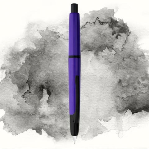 Moonman/Majohn A2 fountain pen, violet with black clip, extra fine nib, click-retractable, displayed vertically on ink splash background.