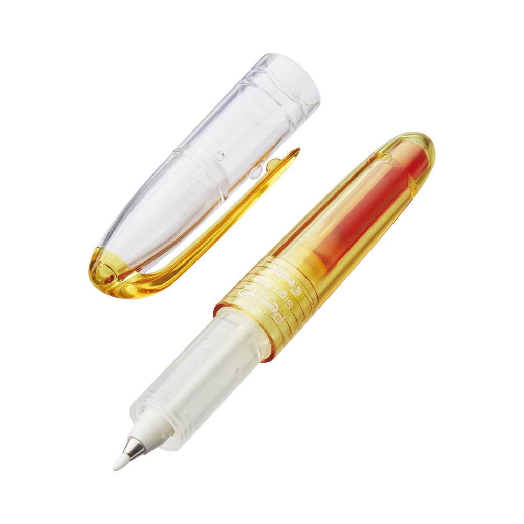 Petit2 Mini Sign Pen - Medium (Orange) with transparent yellow barrel, cap removed, revealing fine applicator tip for precise corrections. Ideal for portable, fun writing.