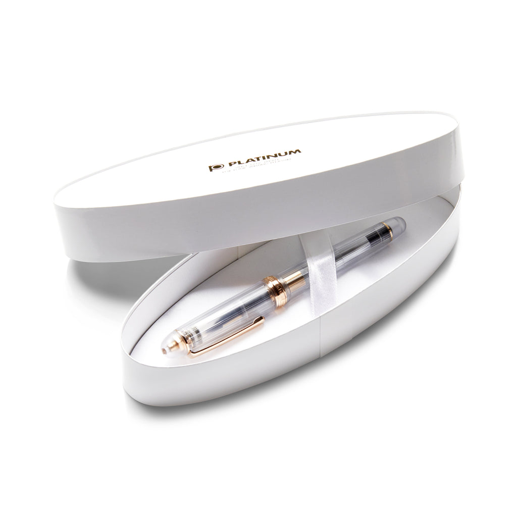 A clear fountain pen with gold trim, #3776 Century Nice Rose Gold - Broad, in a white Platinum logo box, showcasing its elegant design.