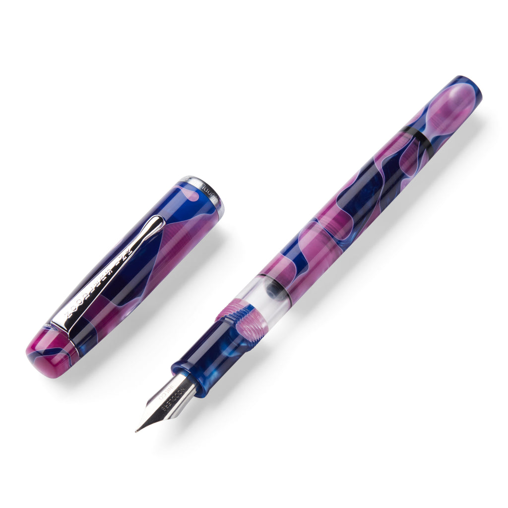 Konrad Acrylic Flex - Tinian Treasure fountain pen in swirled purple-and-pink resin, uncapped, with steel flex nib and clear ink-view window on a white background.