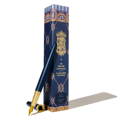 Ferris Wheel Press Brush Fountain Pen - Blue Legacy, gold-tone nib, uncapped, with decorative engraving and jewel-patterned box.
