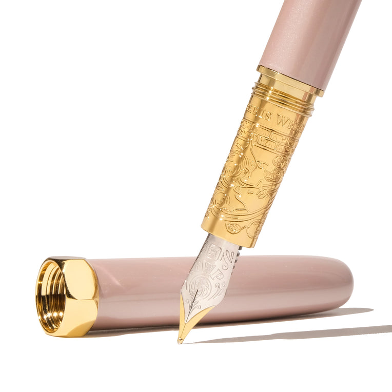 The Bijou Fountain Pen - Huffin Puff Pink (Fine) features a blush-pink barrel, gold-tone accents, and an intricately engraved two-tone nib, epitomizing luxury.