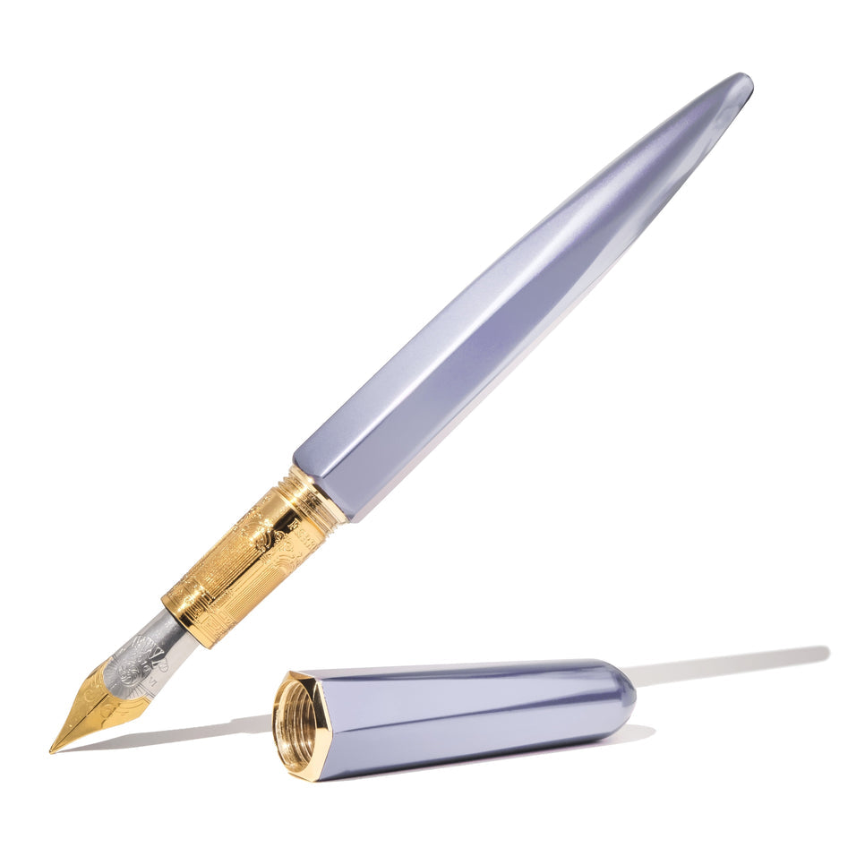 Ferris Wheel Press The Marquise Fountain Pen - Pearl Drop Blue (Fine), features a faceted metallic lavender body with a gold-plated engraved section, and a two-tone nib.