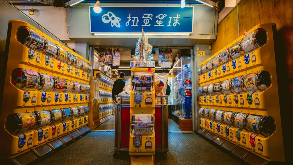 Gachapon Series (Random) - 30ml ink bottles displayed among yellow capsule machines in a vibrant shop aisle, offering a surprise collectible experience.