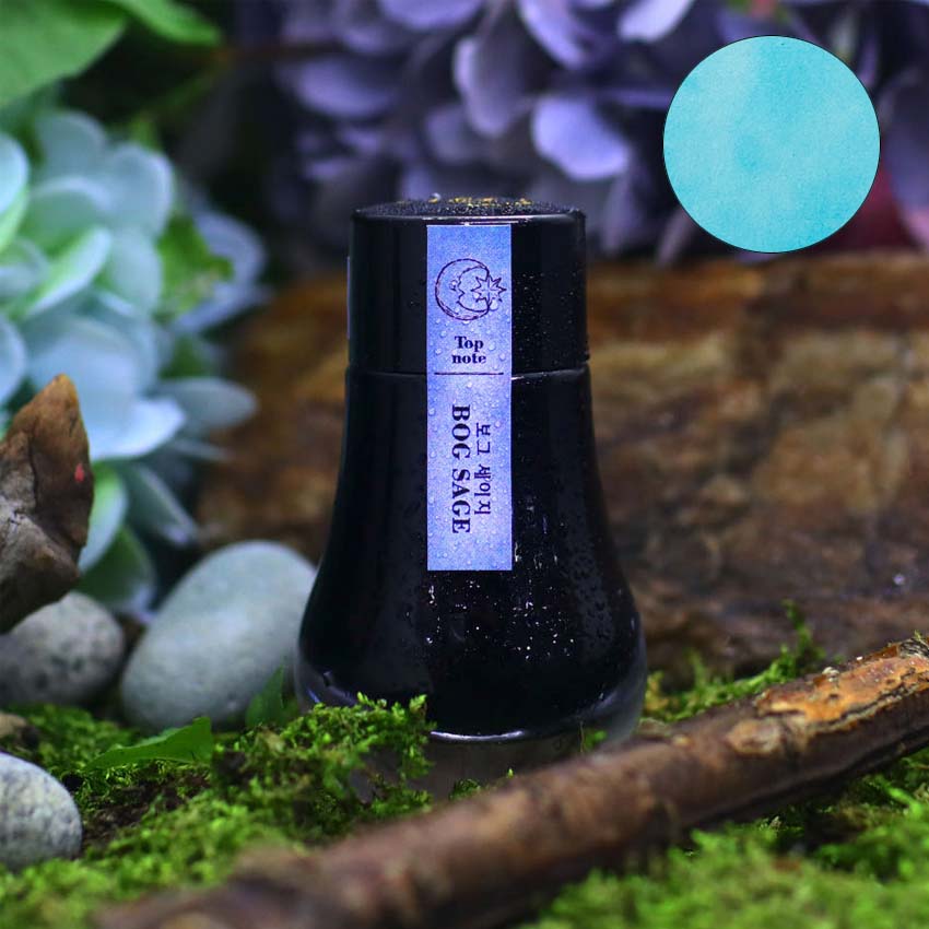 Dominant Industry Bog Sage (Scented) fountain pen ink, 25ml, in a dark-glass bottle on moss with plants and blossoms, featuring pale turquoise/teal color swatch.