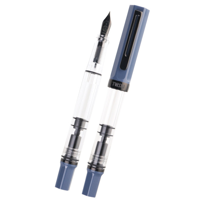 Two TWSBI ECO (Slate Blue/Onyx) - Extra Fine fountain pens, one capped, one uncapped, showcasing clear barrels with visible piston-filling mechanisms and blue end caps.