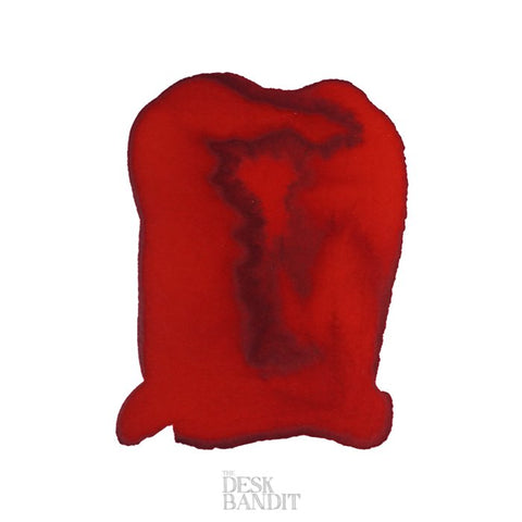Close-up swatch of Robert Oster's Fire Engine Red - 2ml ink, showing a deep center with feathered edges and a subtle Desk Bandit watermark.