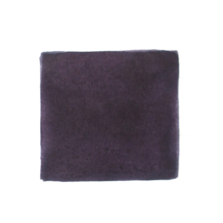 KWZ Ink's Grey Plum fountain pen ink, 60ml, shown in a plush, purplish-gray cloth, exemplifies handcrafted quality and unique color, aligning with Desk Bandit's specialty writing supplies.