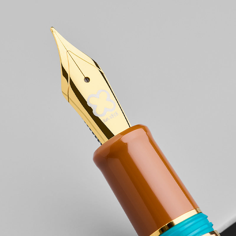 Esterbrook Estie fountain pen in Incredible Rock, showcasing a gold-colored broad nib and turquoise-accented amber section, blending retro charm with modern design.