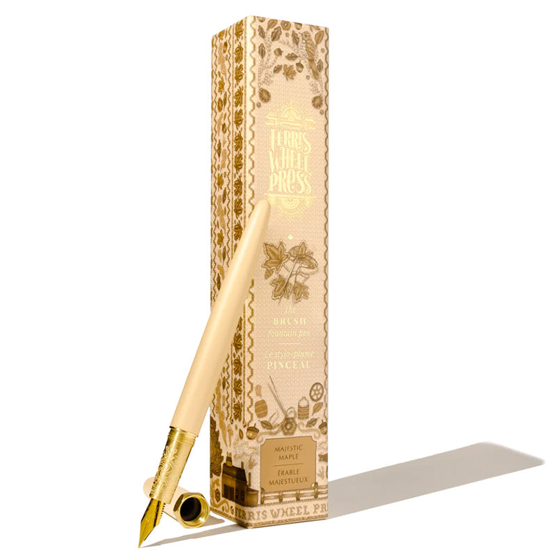 Ferris Wheel Press Brush Fountain Pen - Majestic Maple Satin Series 14k Gold Nib (Fine) with engraved brass grip, leaning against floral-decorated box.