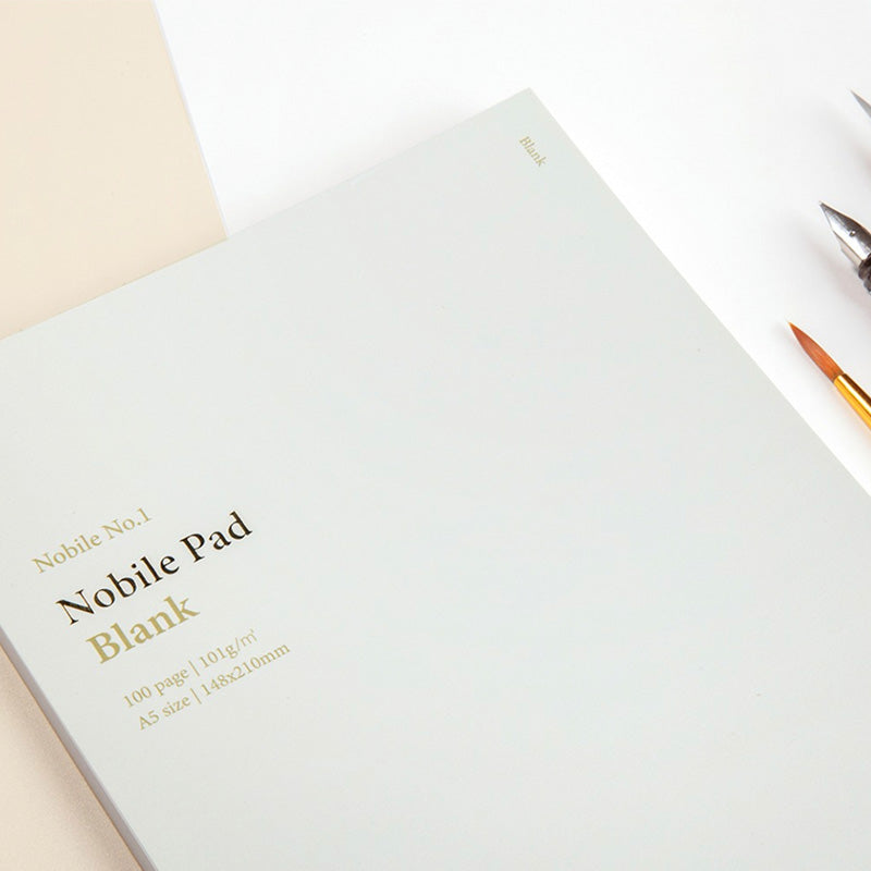 Wearingeul Nobile Notepad - A5 (Blank), featuring 100 pages of fountain pen friendly paper, ideal for sketching or lettering. Includes visible brush and dip-pen nib.