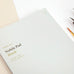 Wearingeul Nobile Notepad - A5 (Blank), featuring 100 pages of fountain pen friendly paper, ideal for sketching or lettering. Includes visible brush and dip-pen nib.