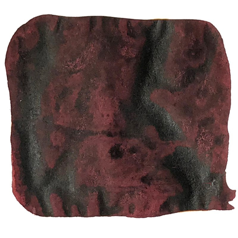 Abstract swatch of mottled maroon with charcoal smudges, representing Noodler's Ink Red Black - 2ml, dye-based and water-resistant for varied writing needs.