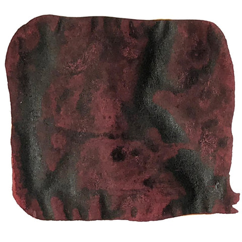 Abstract swatch of mottled maroon with charcoal smudges, representing Noodler's Ink Red Black - 2ml, dye-based and water-resistant for varied writing needs.