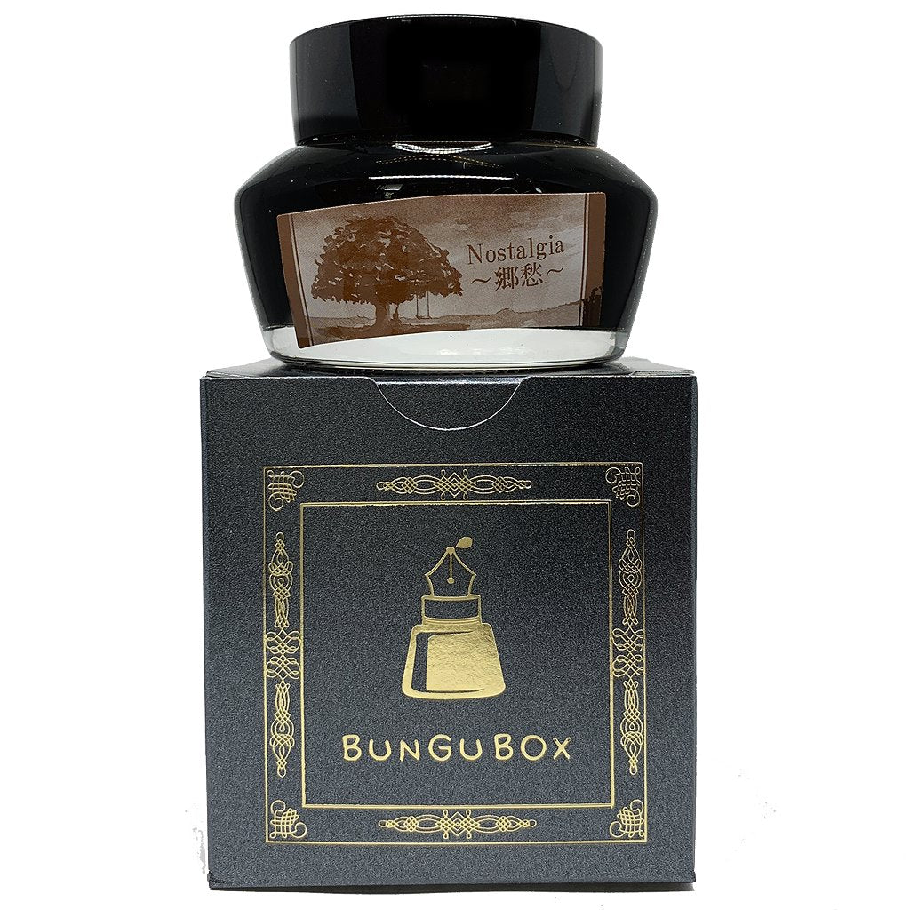 Bungubox Nostalgia - 50ml fountain-pen ink, in a clear glass bottle with sepia label, rests on its dark box with gold accents.