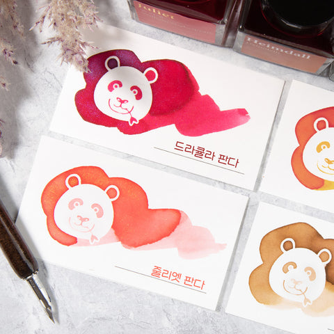 Wearingeul White Panda Ink Swatch Cards flat-lay, showcasing watercolor ink blobs with panda silhouettes. Two ink bottles and a dip-pen nib holder visible. Pack of 50 cards.
