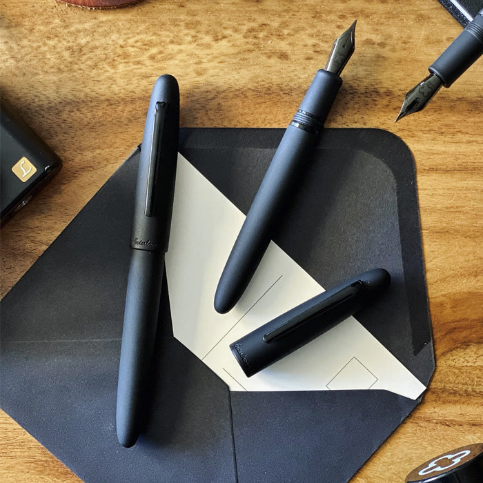 Esterbrook Estie - Raven - Fine fountain pens on a black leather folio, showcasing matte-black finish and steel nib; perfect for writing enthusiasts.