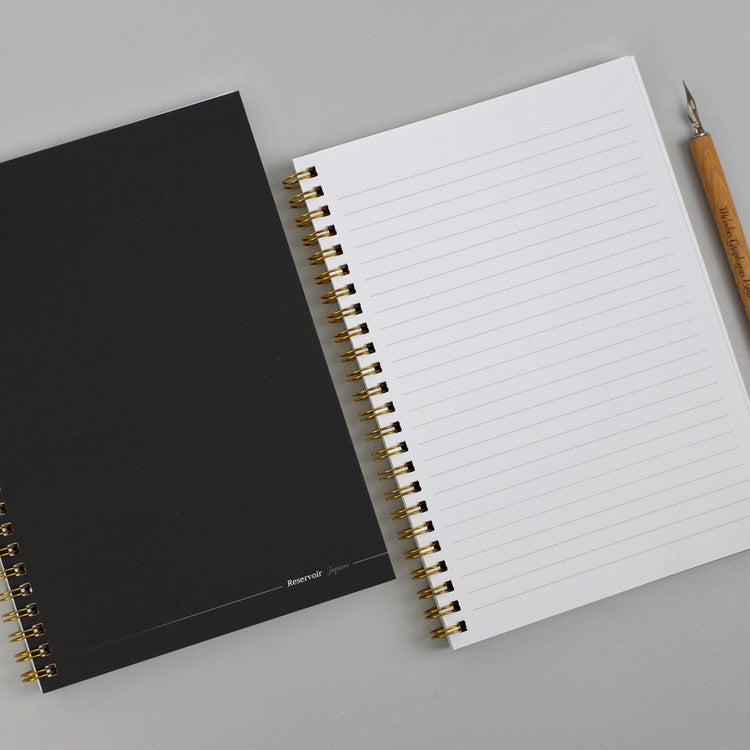 Wearingeul Reservoir Ring Note - A5 (Ruled) notebook with gold spiral binding, shown open with ruled pages and closed with a black cover, alongside a wooden dip-pen nib.