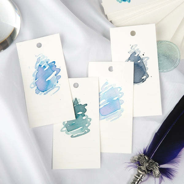 Wearingeul Ink Drop Swatch Cards (Ring Type) with abstract blue and teal ink washes, displayed with a quill pen and glass paperweight. Perfect for showcasing fountain pen ink characteristics.