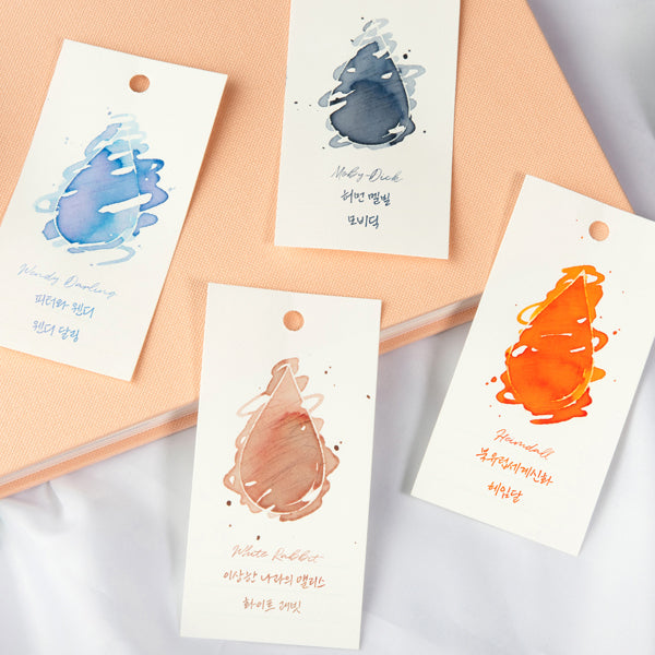 Wearingeul Ink Drop Swatch Cards, featuring five watercolor swatches on white tags, demonstrate fountain pen ink shades, perfect for color sampling and organization.