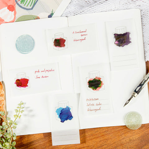 Wearingeul Tracing Ink Swatch Cards (Vertical), featuring ink outlines and handwritten names, accompanied by a dip-pen nib, succulent, pigment samples, and patterned paper scraps.