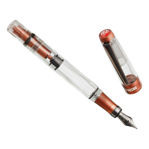 Diamond 580 ALR (Affogato with Onyx) - Stub 1.1 fountain pen featuring a clear barrel, piston mechanism, and orange metal accents, showcasing its elegant design and functionality.