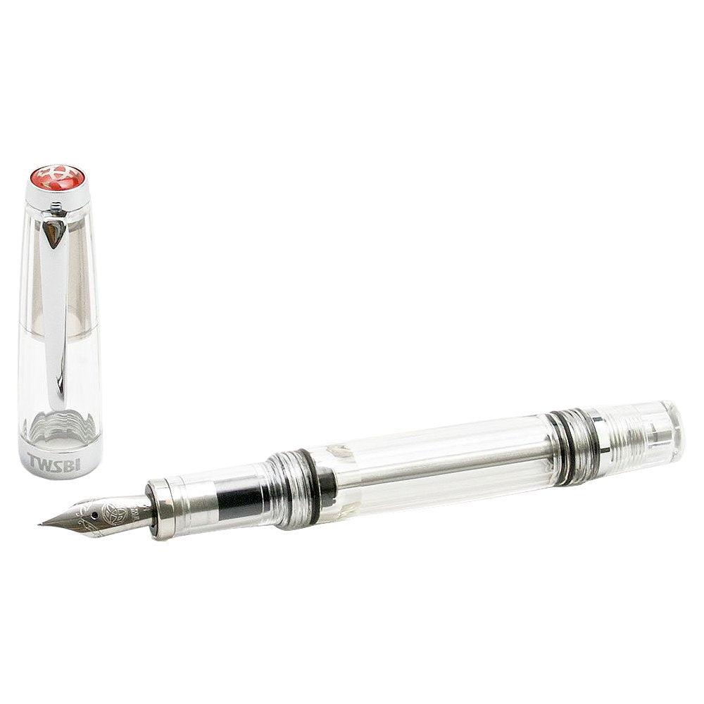 VAC Mini (Clear) - Broad, a TWSBI fountain pen with a transparent body, showcasing the vacuum system and steel nib; cap removed and placed beside the barrel.