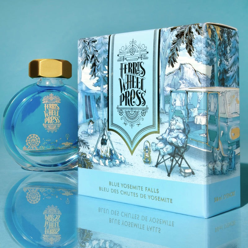 Ferris Wheel Press Blue Yosemite Falls 38ml fountain pen ink in a round glass bottle with a gold cap, alongside its illustrated box featuring a camping scene.