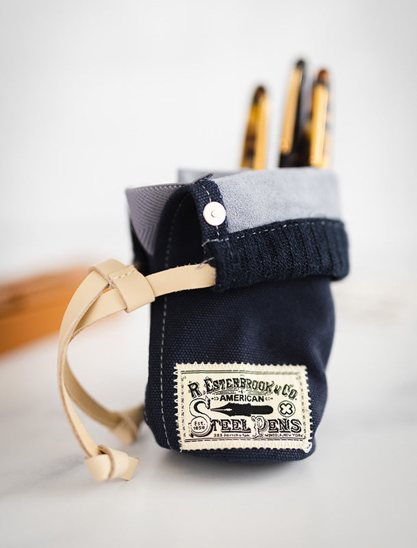 Esterbrook 2GO Cup (Navy Blue) featuring a canvas pouch with a suede cuff and leather drawstring, holding pens upright for portable desk use.