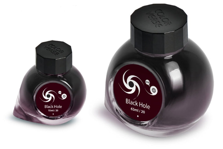 Two glass bottles of Colorverse Black Hole ink, 65ml and 15ml, with octagonal caps and galaxy swirl labels, from the Astrophysics Collection.
