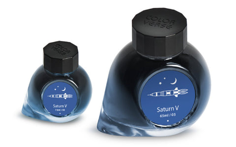Two glass bottles of Colorverse Saturn V ink, 65ml and 15ml, with black caps, featuring a Saturn V rocket design on blue labels.