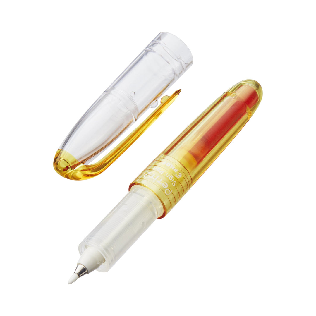 Petit2 Mini Sign Pen - Medium (Orange) with transparent yellow barrel, cap removed, revealing fine applicator tip for precise corrections. Ideal for portable, fun writing.