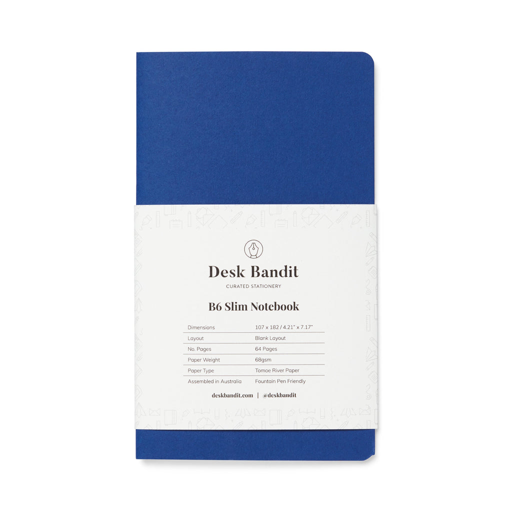 Tomoe River 68gsm Notebook - B6 Slim (Blank) with a blue cover and removable white band displaying Desk Bandit logo and product details.