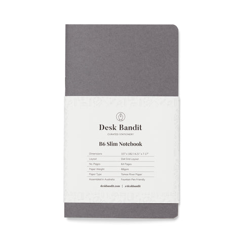 Japanese-Milled 64gsm Notebook - B6 Slim (Dot Grid) with dark gray soft cover, white paper band, and 64 pages of fountain pen friendly paper.