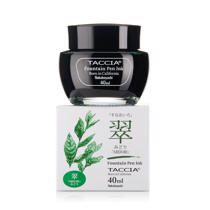 Midori - 2ml: A glass jar of TACCiA fountain-pen ink in green, resting on a box with botanical artwork and Japanese text.