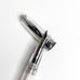 Ahab Flex - Clear Demonstrator fountain pen with exposed flexible steel nib and transparent barrel, alongside its shiny metal cap, showcasing versatile filling options.