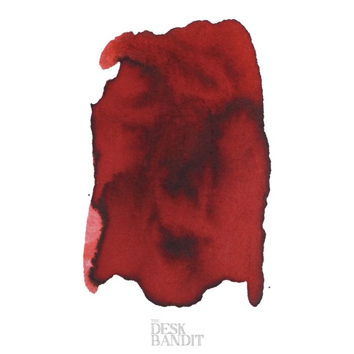 Swatch of Robert Oster's Burgundy ink in 2ml, showing deep red hues with darker pooled areas and irregular edges on white paper.