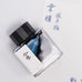 Fanyantan Cloud Pavilion 2ml fountain pen ink sample in a square bottle with a black cap, surrounded by blue calligraphy on white paper, showcasing artistic depth.