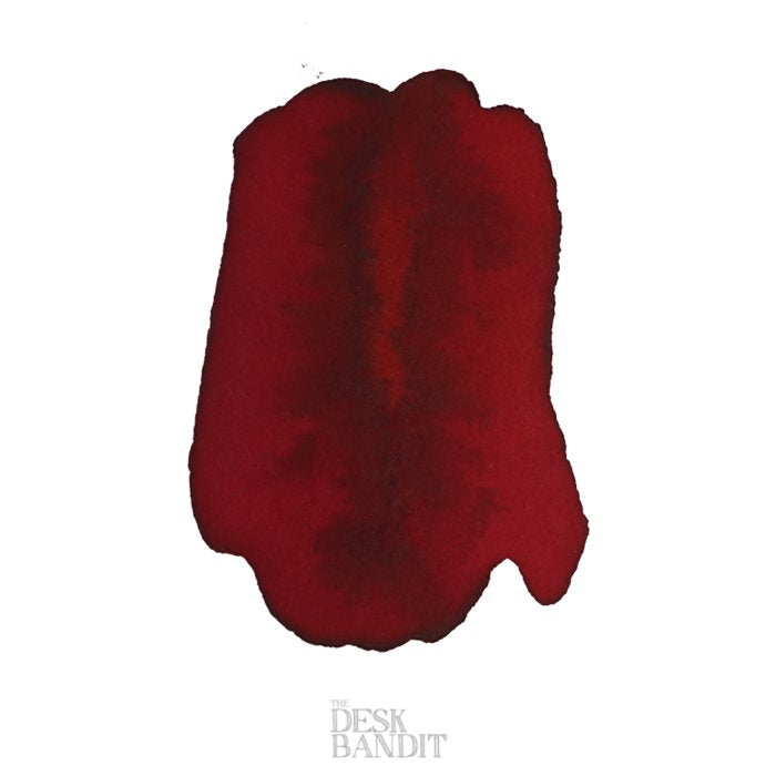 Swatch of Robert Oster's Crimson - 2ml, showcasing pooling and shading effects on white paper, with The Desk Bandit watermark visible.