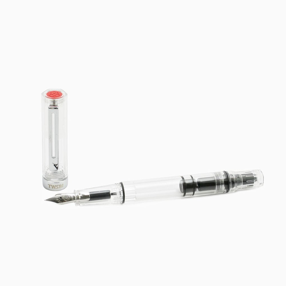 ECO-T (Clear) - Stub 1.1mm fountain pen with transparent barrel, displaying piston-filling mechanism, stainless steel nib, and clear cap with red-emblemed TWSBI logo.