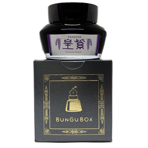 Bungubox Imperial Purple fountain-pen ink bottle atop its black and gold packaging, highlighting the 50ml dye-based ink's elegance and specialty branding.