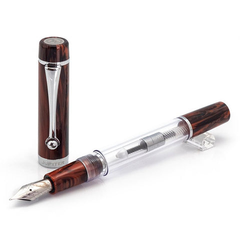 Planet Series (Jupiter) - Medium: A clear demonstrator fountain pen with a marbled brown cap, visible piston-filling mechanism, and stainless steel nib.