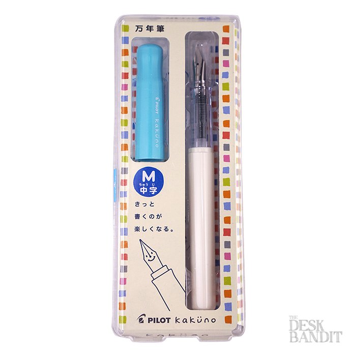 Pilot Kakuno fountain pen in blister pack, featuring a white barrel, translucent grip, medium nib, and light-blue cap with included black ink cartridge.