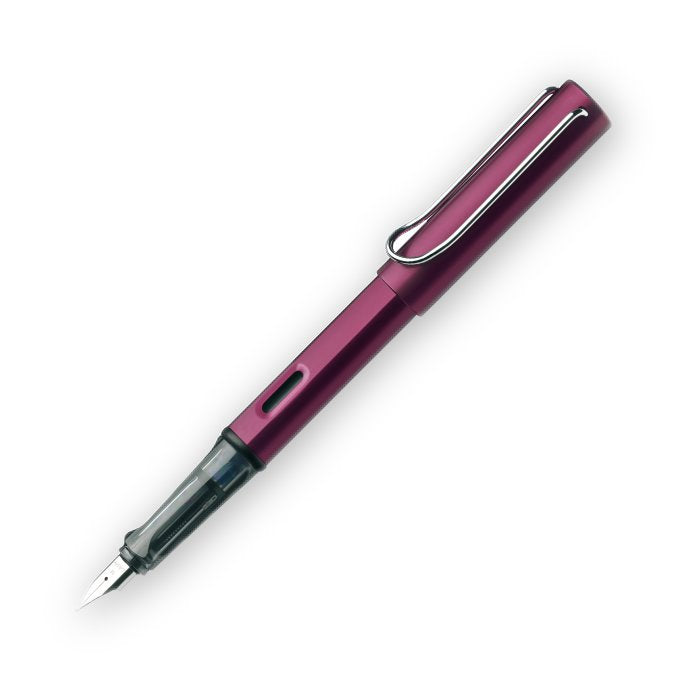 Purple metal-bodied Lamy AL-Star fountain pen, featuring a clear grip, stainless-steel nib, and clip, designed for improved penmanship; includes extra fine nib and blue ink cartridge.