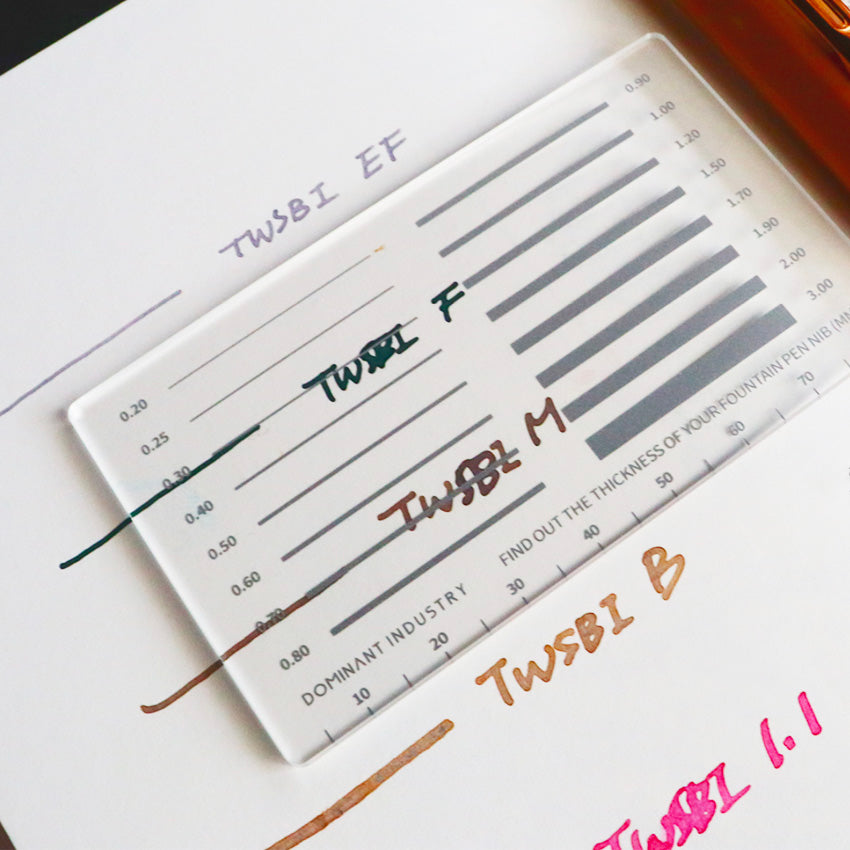 Measure My Pen MM Pad by Dominant Industry, a translucent gauge for measuring fountain pen nib widths, shown on paper with ink swatches and handwritten labels.