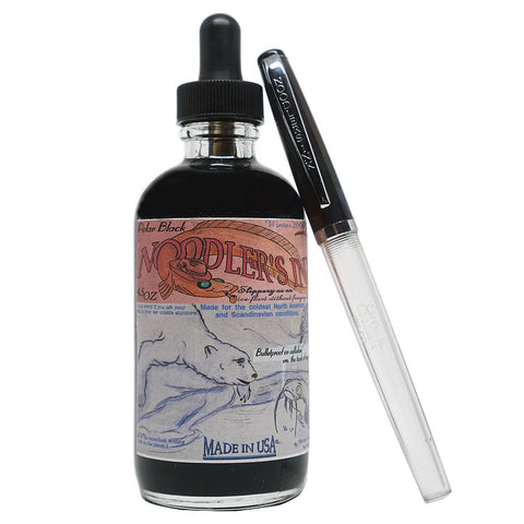 Noodler's Polar Black 133ml ink with a glass dropper top, accompanied by a clear-barrel Noodler’s fountain pen with a black cap.