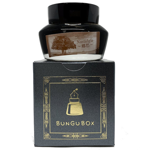 Bungubox Nostalgia - 50ml fountain-pen ink, in a clear glass bottle with sepia label, rests on its dark box with gold accents.