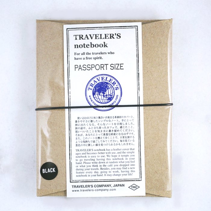 Passport Leather Cover (Black) by Traveler’s Company, Japan, sealed in a brown kraft sleeve with a white label, secured by a black elastic band.